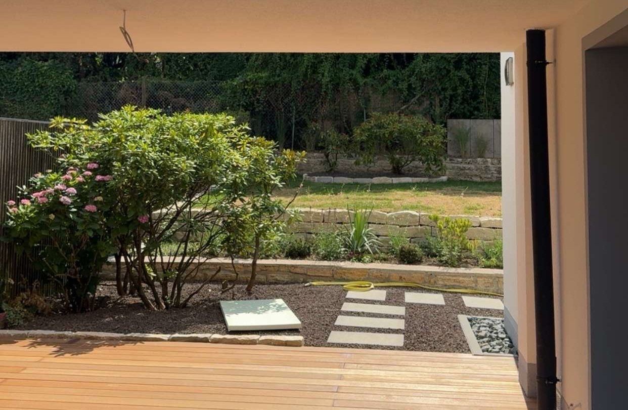 Blick von der überdachten Terrasse in den Garten des sanierten KfW-Effizienzhauses